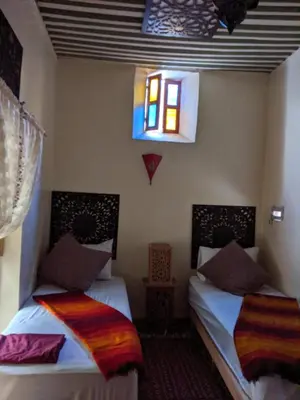 two beds in a room with a window at Dar nadaa in Fès