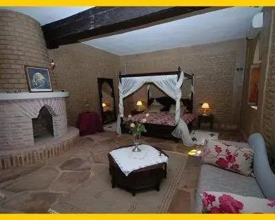 a living room with a bed and a fireplace at La Rose Du Desert in Erfoud