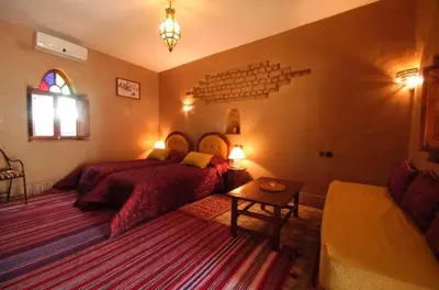 a bedroom with a bed and a table and a couch at La Rose Du Desert in Erfoud