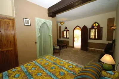 a bedroom with a large bed and a living room at La Rose Du Desert in Erfoud