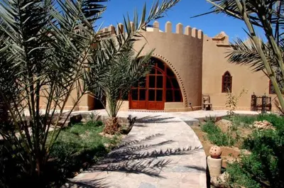 a house with a palm tree in front of it at La Rose Du Desert in Erfoud