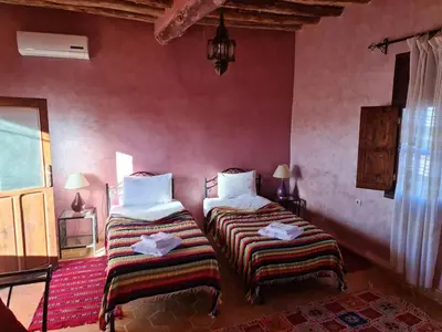 two beds in a room with red walls at Chez Laila in Skoura