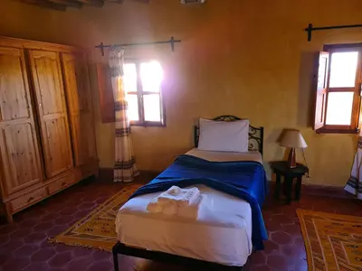 a bedroom with a bed and two windows at Chez Laila in Skoura
