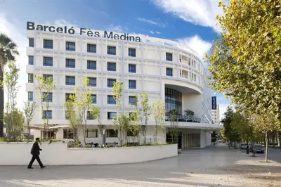 a woman walking in front of a white building at Barceló Fès Medina in Fès