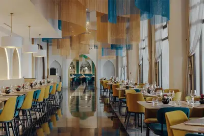 a dining room with tables and chairs and a hallway at Barceló Fès Medina in Fès