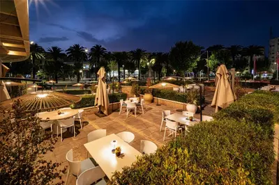 a restaurant with tables and white chairs and umbrellas at Barceló Fès Medina in Fès