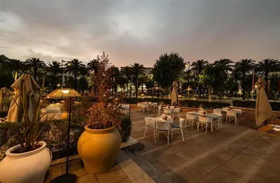 a patio with tables and chairs and umbrellas at Barceló Fès Medina in Fès