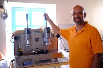 a man in an orange shirt standing next to a machine at Kasbah Imini Restaurant & Hotel in Taourirt