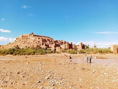 a group of people standing on a beach with a building at Kasbah Imini Restaurant & Hotel in Taourirt