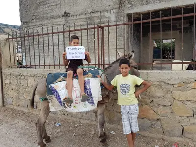 a boy holding a sign next to a boy on a donkey at Dar Zerhoune in Moulay Idriss Zerhoun