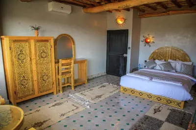 a bedroom with a bed and a wooden dresser at Taloute Ecolodge in Skoura