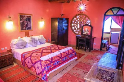 a bedroom with a bed and a table and a mirror at Taloute Ecolodge in Skoura