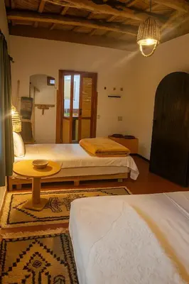 a bedroom with two beds and a table in it at Riad pizzeria Marhaba in Akhendachou nʼAït Ouffi