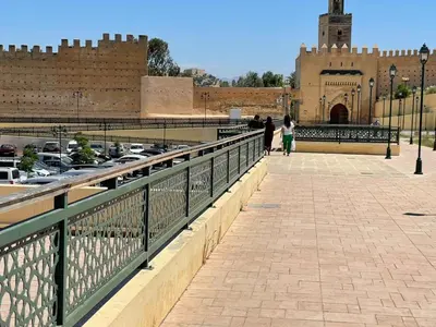 a woman walking across a bridge with a castle in the background at Dar La Bague de Kenza in Fès