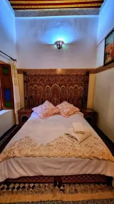 a bedroom with a large bed with a wooden headboard at Dar La Bague de Kenza in Fès