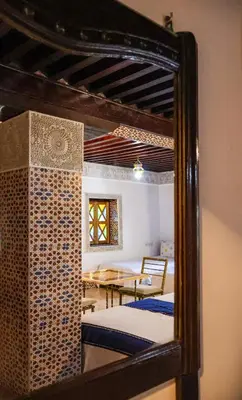 a mirror reflection of a dining room with a table at Riad Mounana fez 13th century luxury palace& spa in Fès