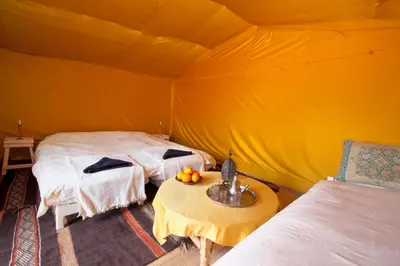 a room with two beds and a table in a tent at Bivouac La Dune Blanche in Mhamid