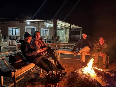 a group of people sitting around a fire at Bivouac La Dune Blanche in Mhamid