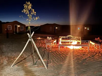 a tripod with a table and chairs at night at Bivouac La Dune Blanche in Mhamid