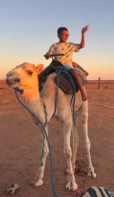 a man riding on the back of a camel at Bivouac La Dune Blanche in Mhamid