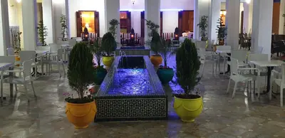 a pool of water in a room with potted plants at Hotel Batha in Fès