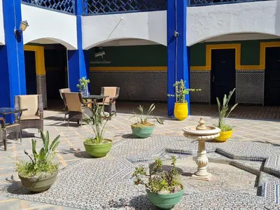 a courtyard with chairs and tables and potted plants at Hotel Batha in Fès