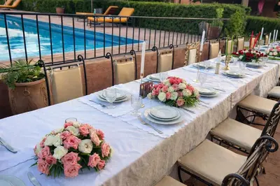a long table with flowers on it with a pool at Les Orangers De l'Ourika in Marrakech