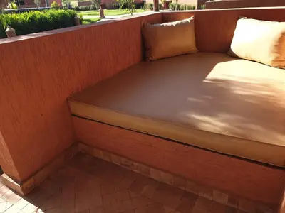 a wooden bench with two pillows on a porch at Les Orangers De l'Ourika in Marrakech