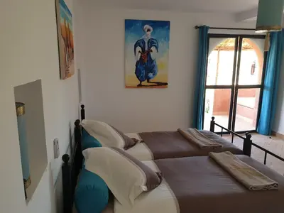 a bedroom with two beds and a painting on the wall at Les Orangers De l'Ourika in Marrakech