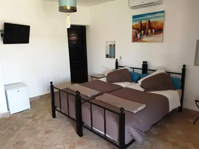 a large bed in a room with a tv at Les Orangers De l'Ourika in Marrakech