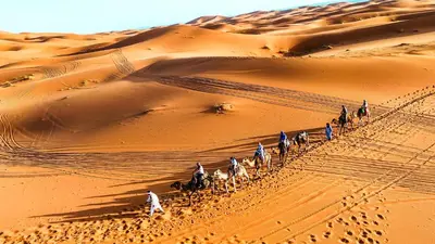 a group of people riding horses in the desert at Moonlight Luxury Camp in Merzouga