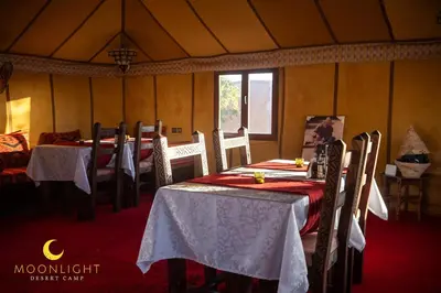 a dining room with tables and chairs in a tent at Moonlight Luxury Camp in Merzouga
