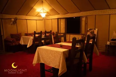 a dining room with tables and chairs in a tent at Moonlight Luxury Camp in Merzouga
