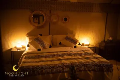 a bedroom with a bed with two lights on it at Moonlight Luxury Camp in Merzouga