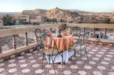 a table and chairs on a balcony with a view at Kasbah Valentine in Aït Ben Haddou