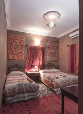 a hotel room with two beds and a table at Kasbah Valentine in Aït Ben Haddou