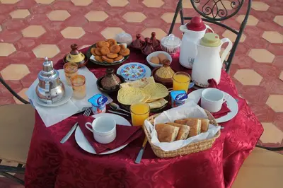 a table with breakfast food on a red table cloth at Kasbah Valentine in Aït Ben Haddou