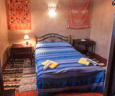 a bedroom with a bed with two tables and two towels at Kasbah Valentine in Aït Ben Haddou