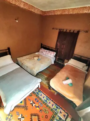a room with three beds and a rug at auberge restaurant tizgui in Tinerhir