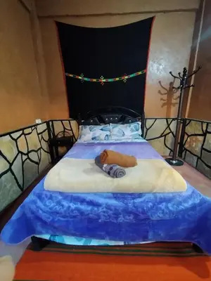 a bedroom with a bed with a blue comforter at auberge restaurant tizgui in Tinerhir