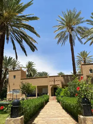 a building with palm trees and a walkway at Maison d Hôte Ighrem in Goulmima