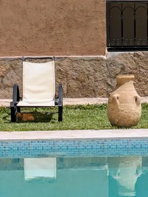 a chair sitting next to a pool next to a vase at Maison d Hôte Ighrem in Goulmima