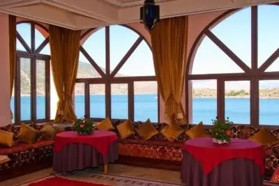 a living room with a couch and windows at Chems Du Lac Bin El Ouidane in Bine el Ouidane