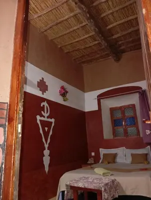 a bedroom with a bed and a cross on the wall at Kasbah tifaoute ait Ben haddou in Aït Ben Haddou