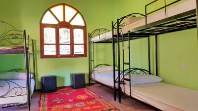 a room with four bunk beds and a window at Dounia Hostel in Tinerhir