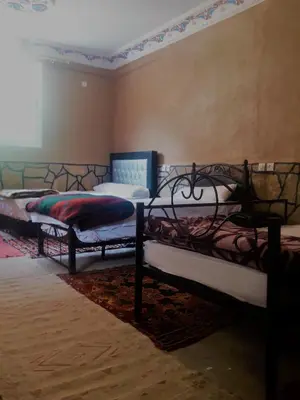 a room with three beds in a room at Dounia Hostel in Tinerhir