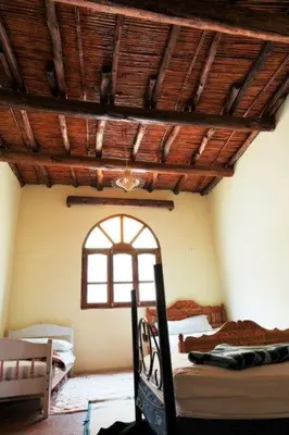 a bedroom with two beds and a wooden ceiling at Dounia Hostel in Tinerhir