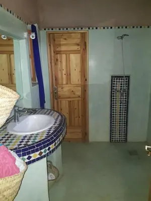 a bathroom with a sink and a wooden door at Dar Paru in Mhamid