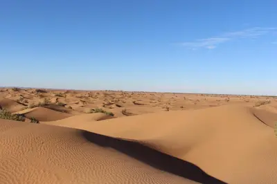 a desert with sand dunes and a blue sky at Dar Paru in Mhamid