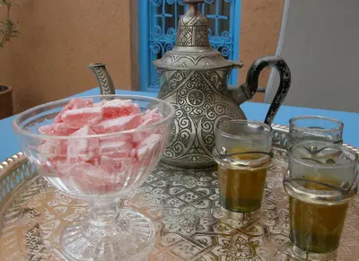 a table with a glass bowl of food and two glasses at Kasbah Iswan in Kalaat MGouna